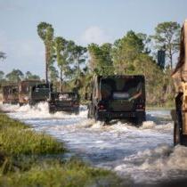 Florida National Guard vehicles mobilizing over a flooded road to provide aid for Hurricane Helene victims.